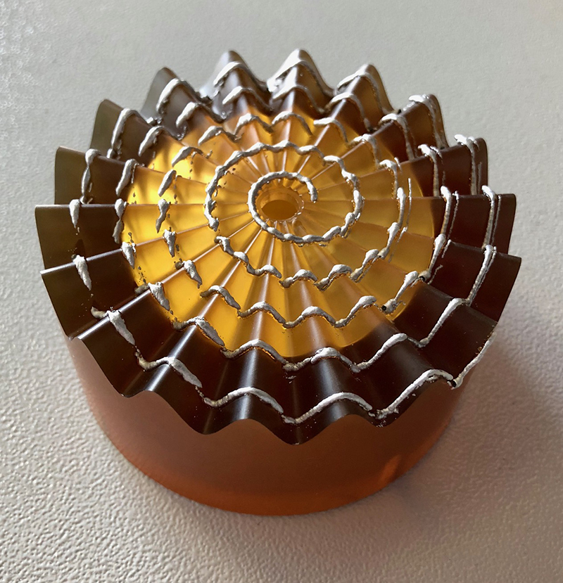 a flower looking item with a yellow interior and a brown exterior and a spiral of silver going from the center out to the edges