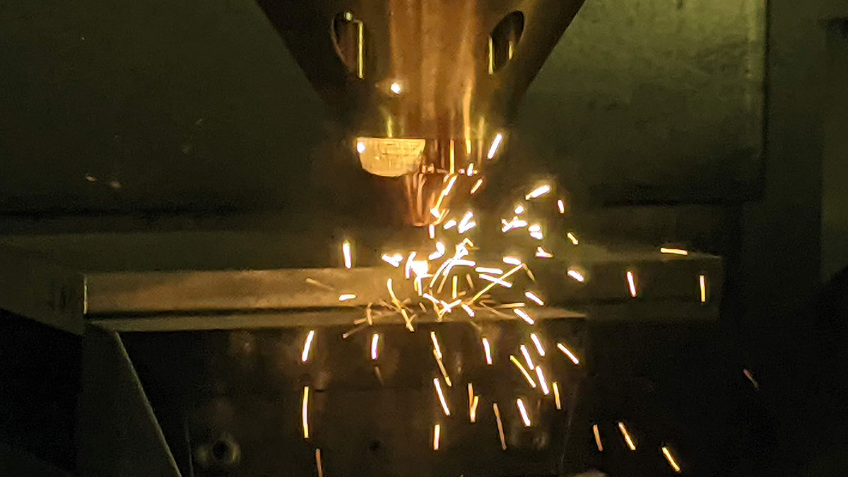 machining equipment throws sparks as it contacts a metal plate.