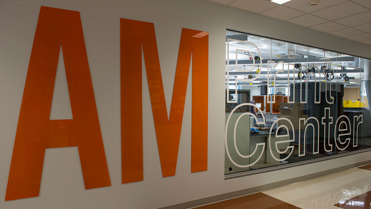 view of a lab from a hallway, with large letters spelling AM Print Center across the wall and windows.