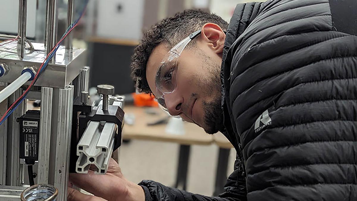 student adjusts machinery in a lab.