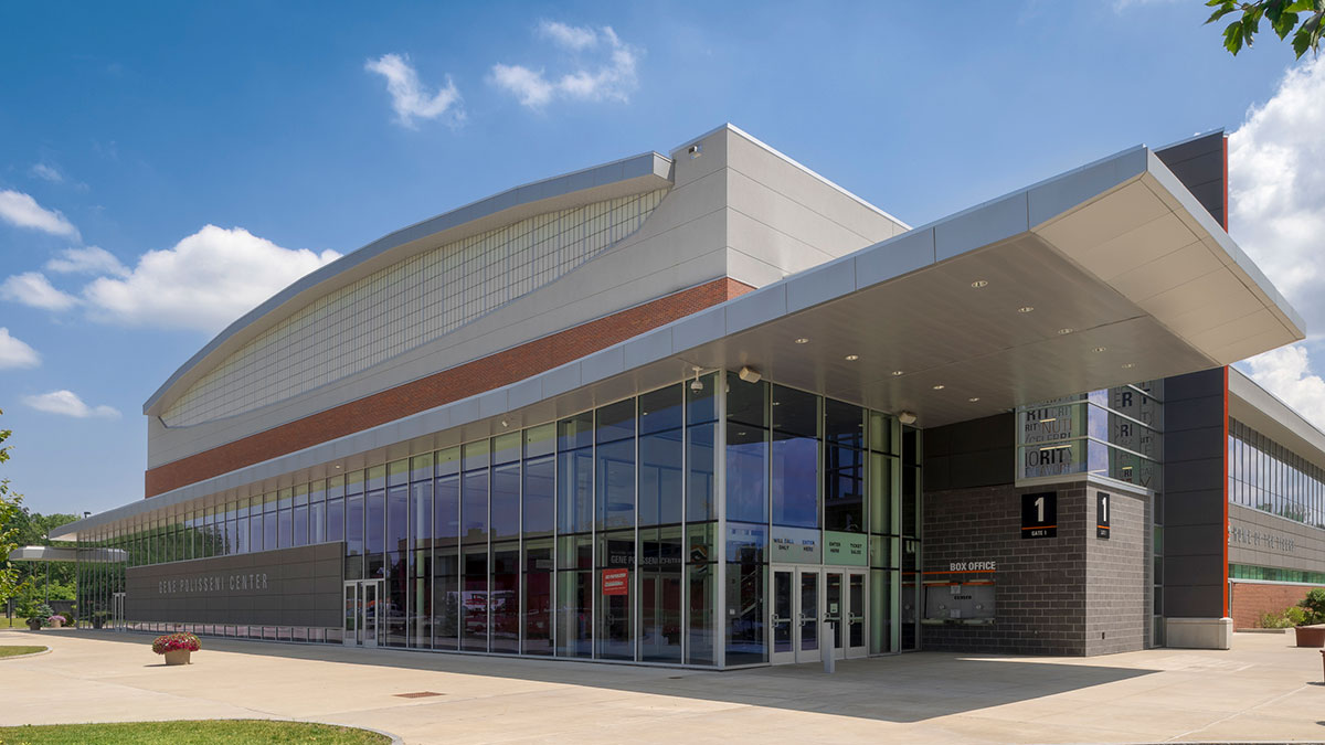 The exterior of the Gene Polisseni Center on a sunny day with a modern glass facade and entrance canopy.
