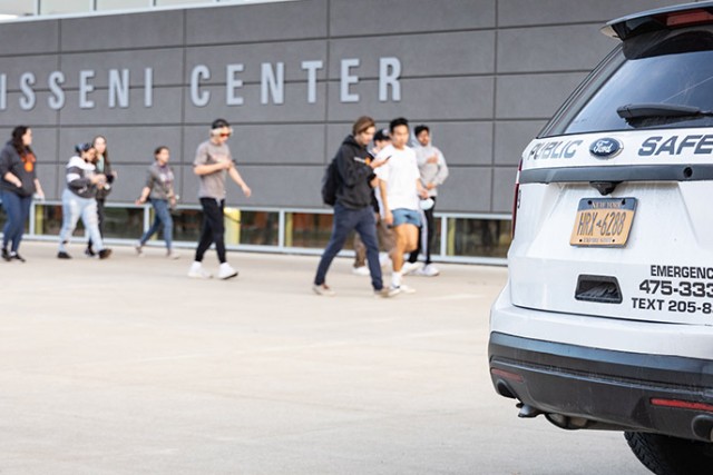 a white SUV that has Public Safety logos on it sits in front of the Gene Polisseni Center.