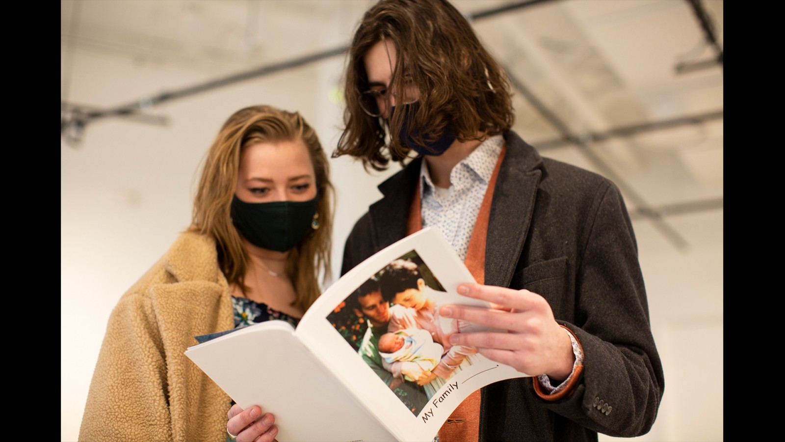 Two students look at a photo book together. 