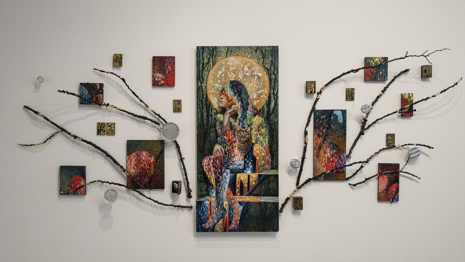 A dozen paintings hang on a wall.