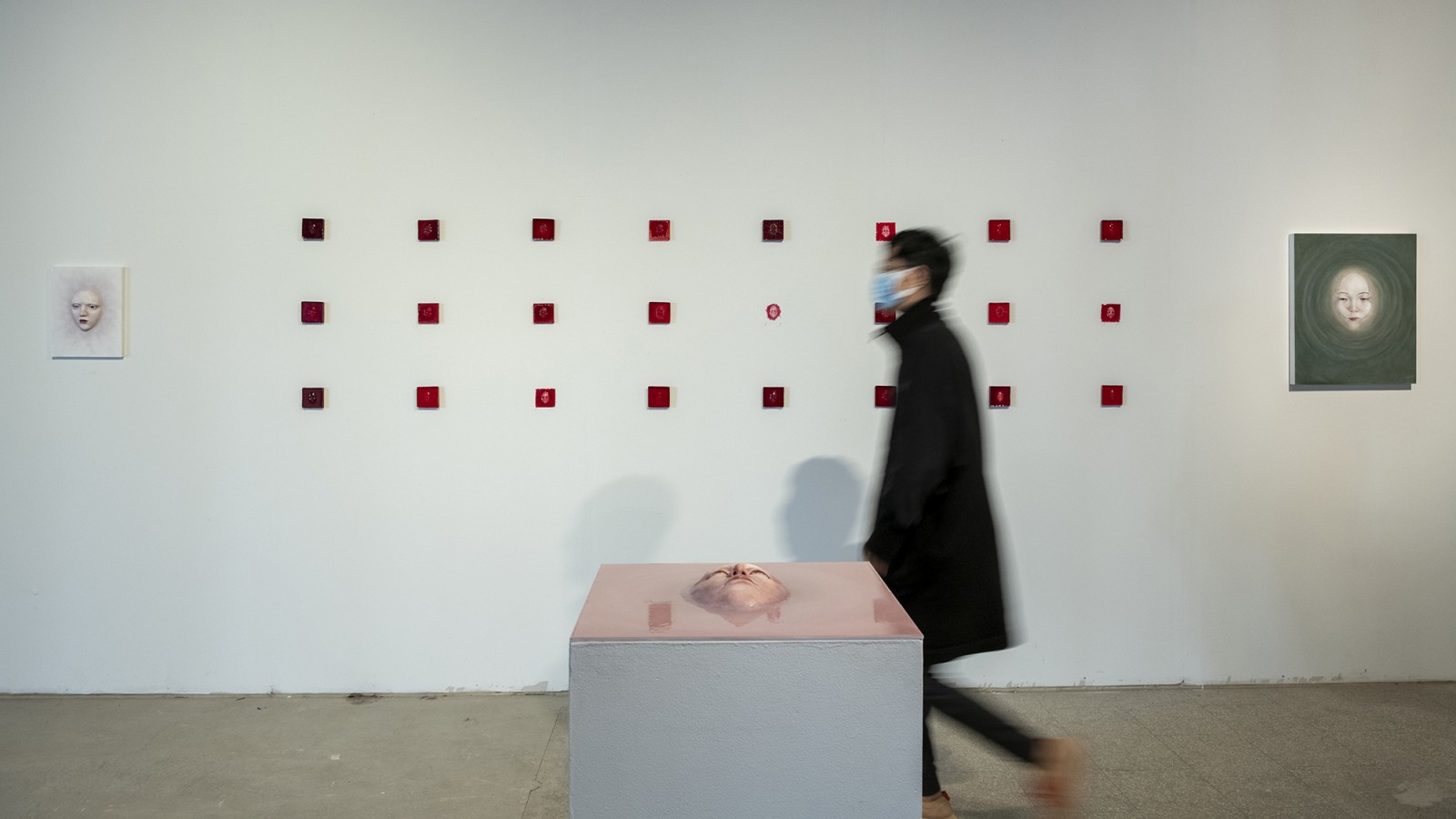 A gallery visitor walks in front of sculptures.