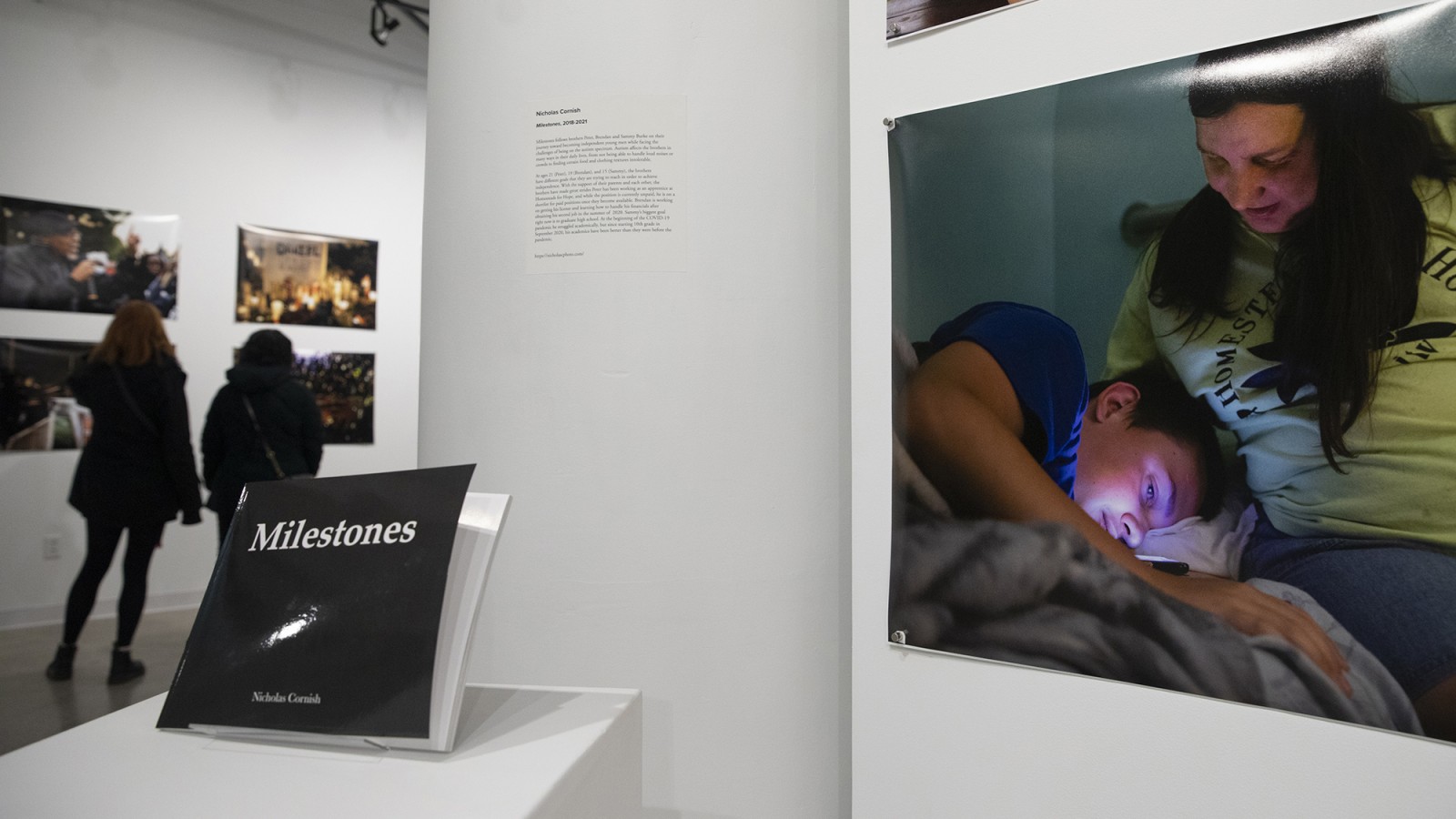 A display of photos on walls and a book on a stand.