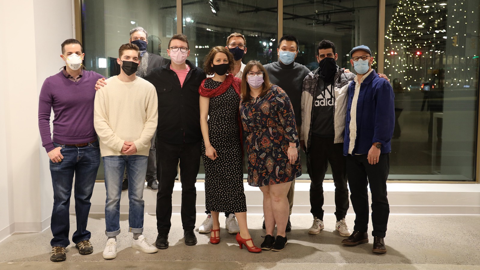 A group of people pose for a photo in front of a window.