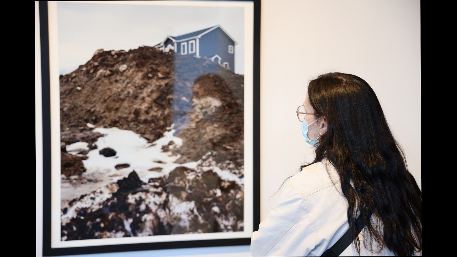 A gallery visitor observes a landscape photo.