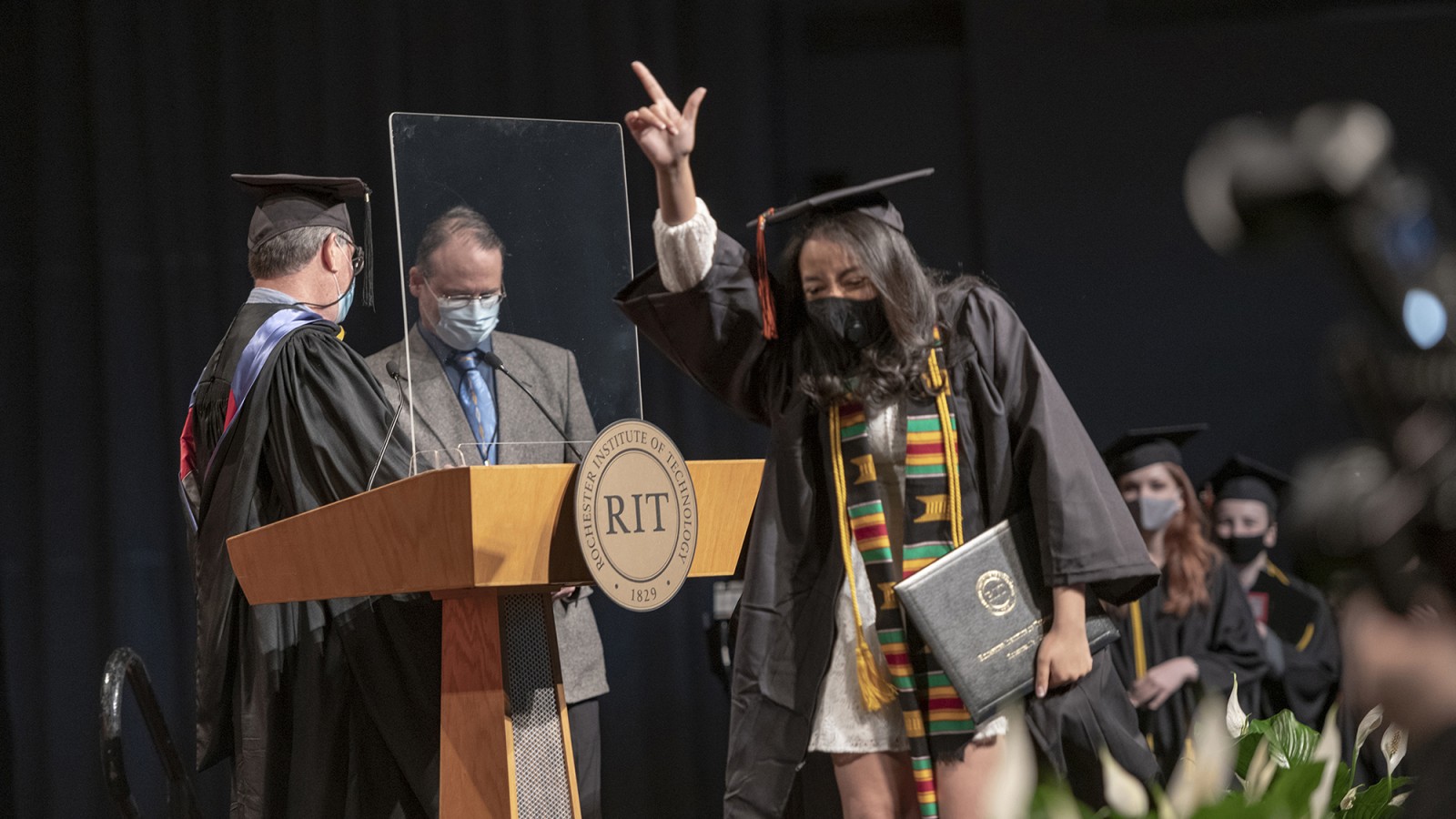A student celebrates on stage after receiving a diploma.