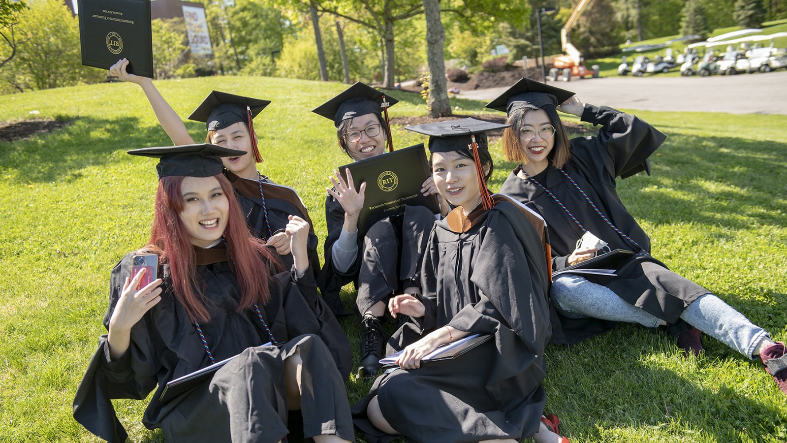 A group of students holding diplomas smiles.