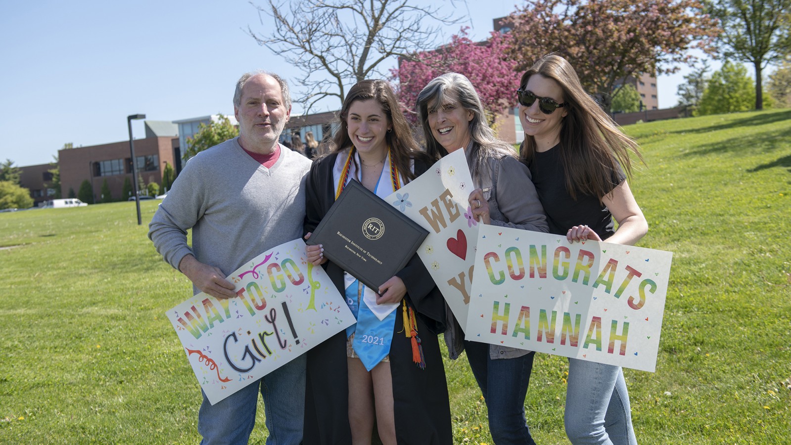 A family of four holding signs poses for a photo.