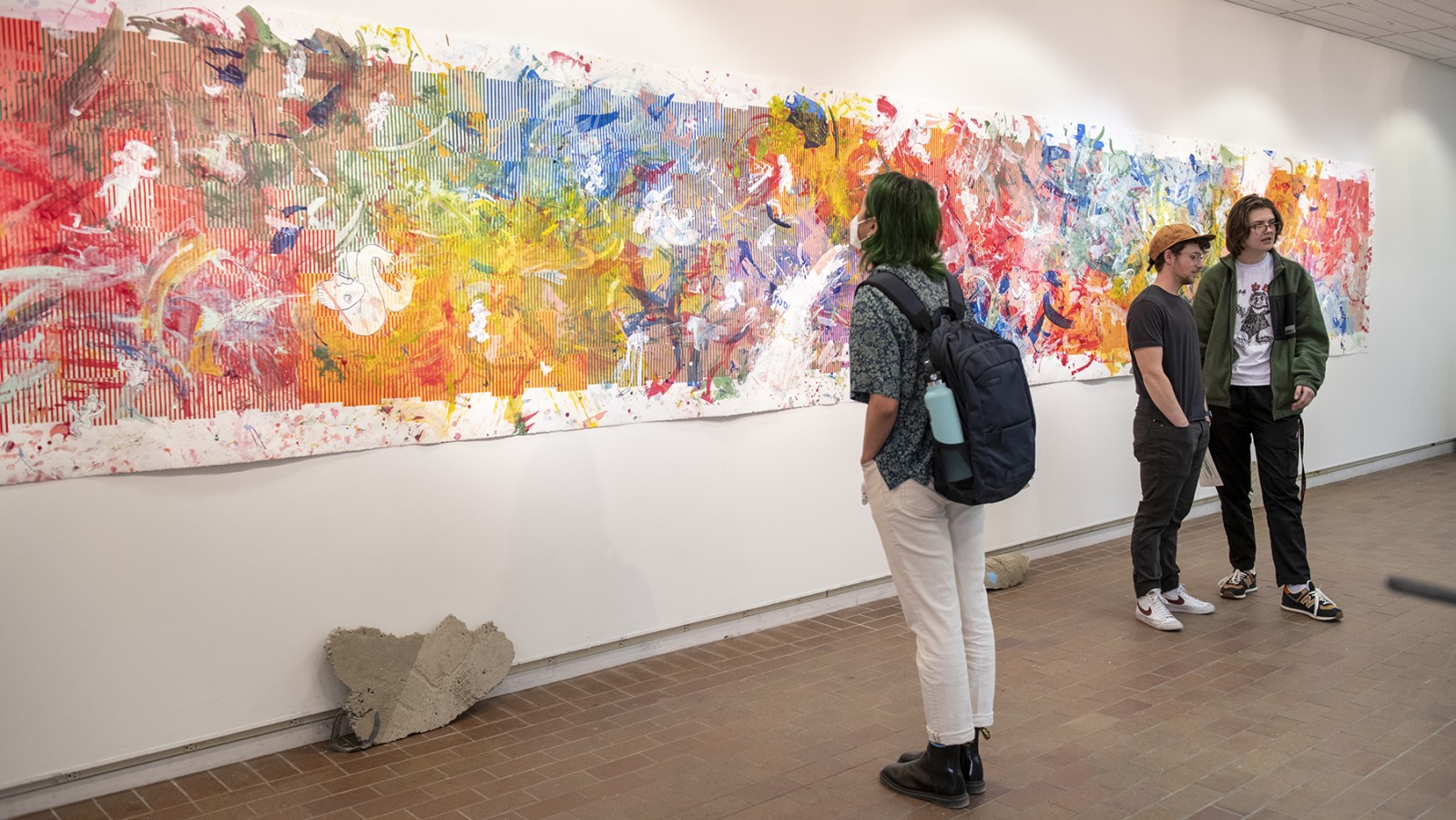 Gallery visitors check out a wall-spanning printmaking work.