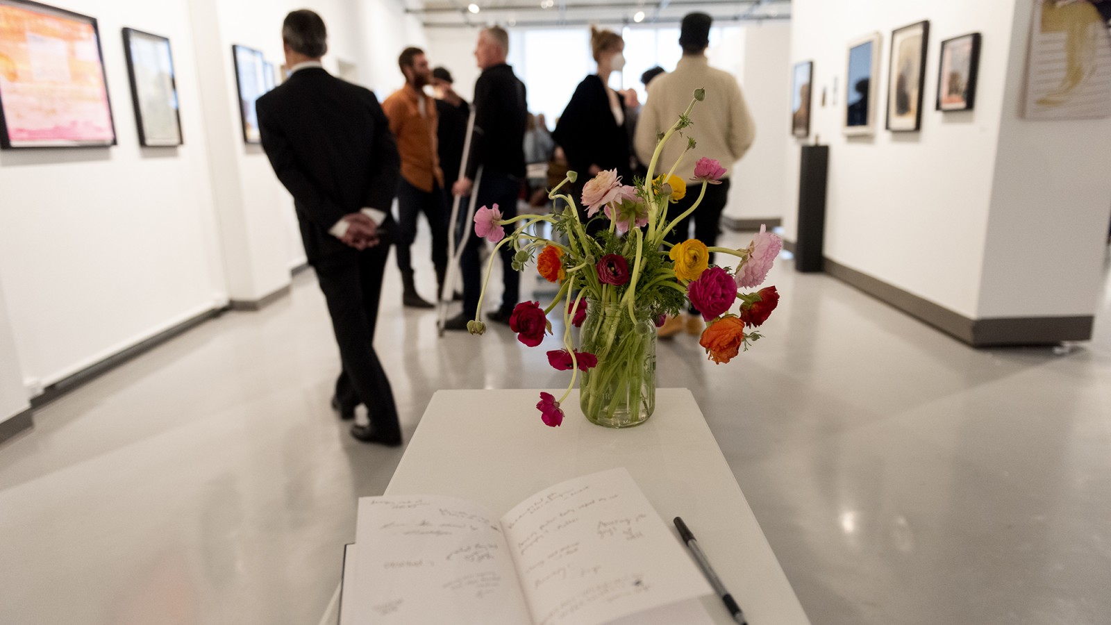 Flowers in the foreground, photos on gallery walls in the background.