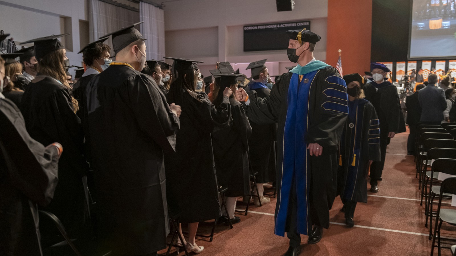 Dean Todd Jokl fist bumps graduate candidates.