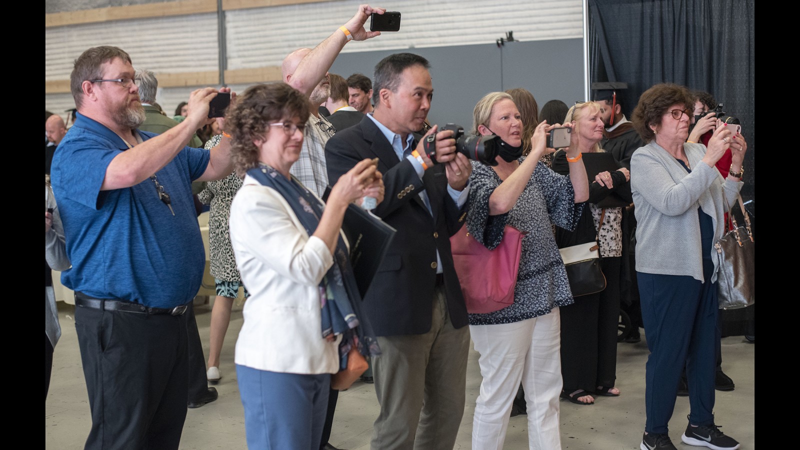 Family and friends take photos of posing new graduates.