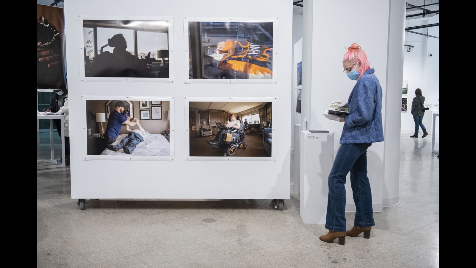 A gallery visitor looks at photos on a wall.