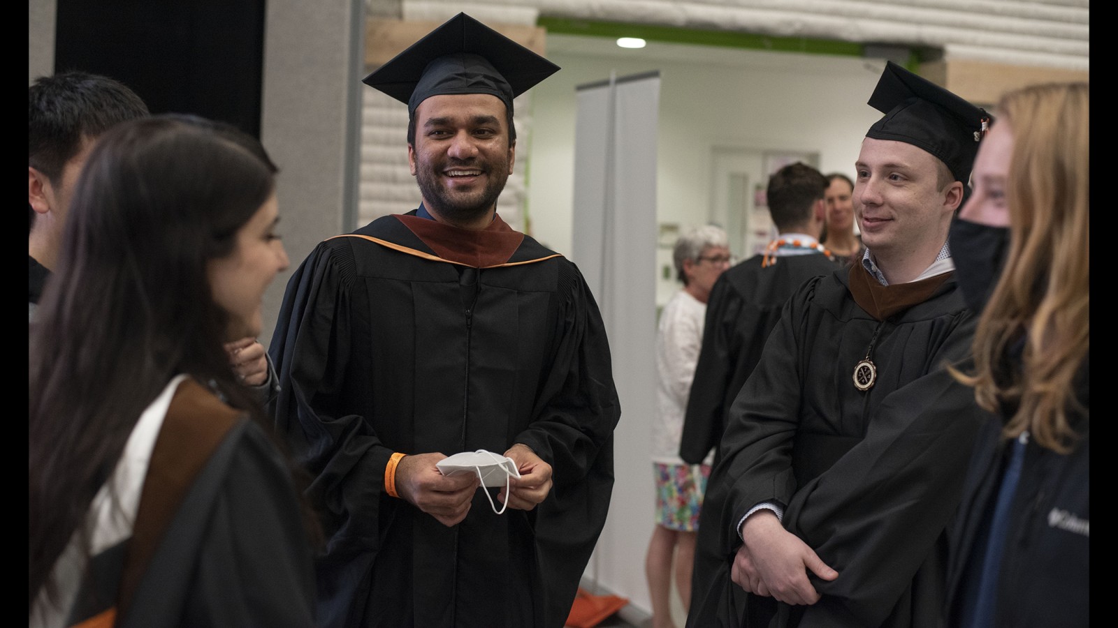 Faculty and new graduates talk in a circle.