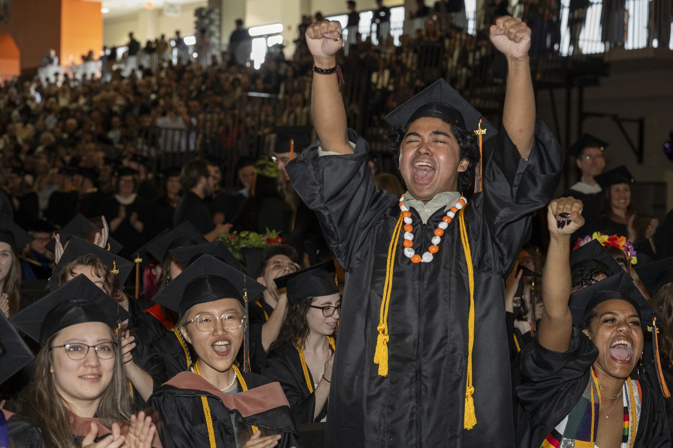 A student raises their arms high in the air.
