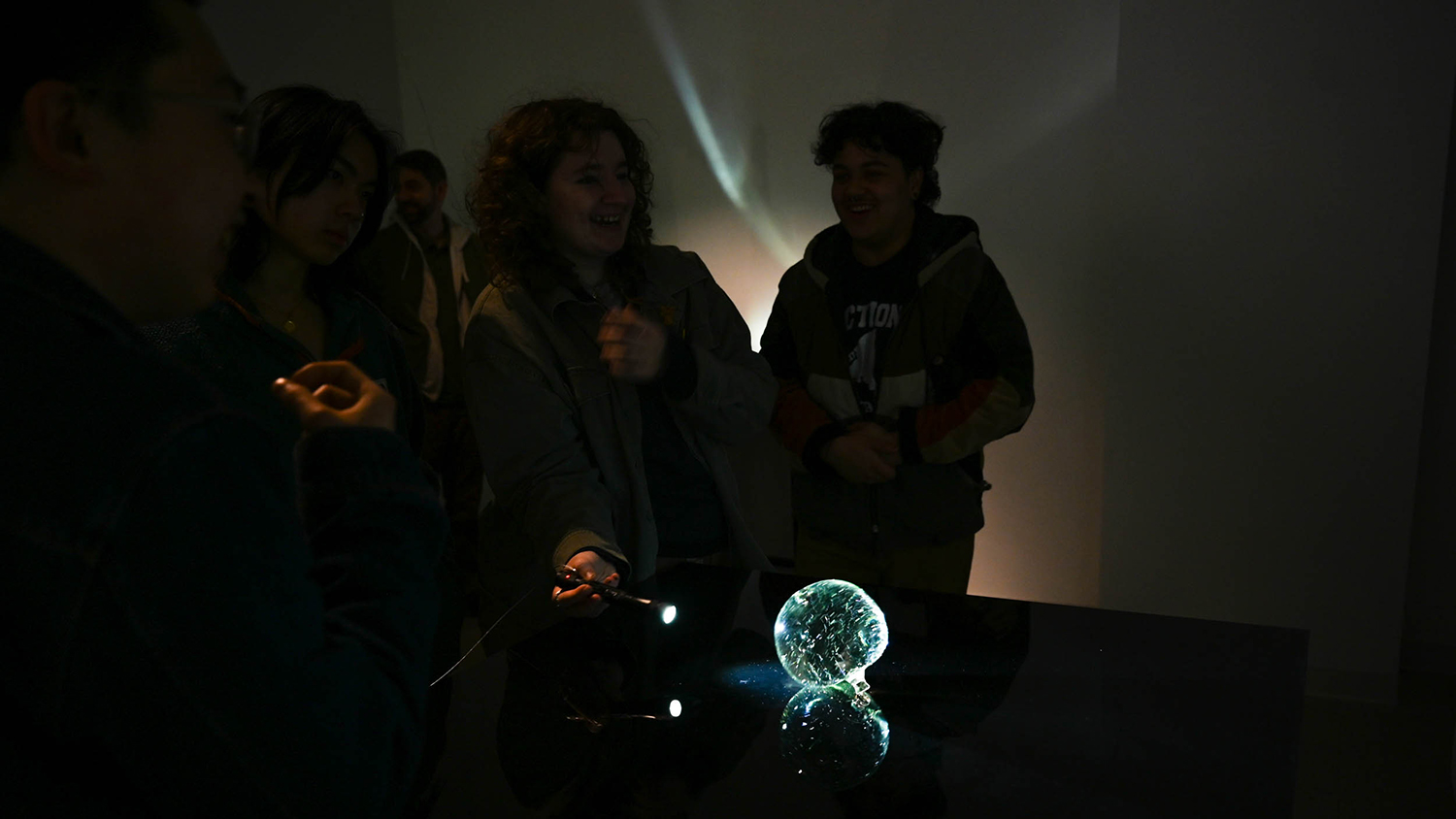 A glass piece reflects a flashlight light shining on it.