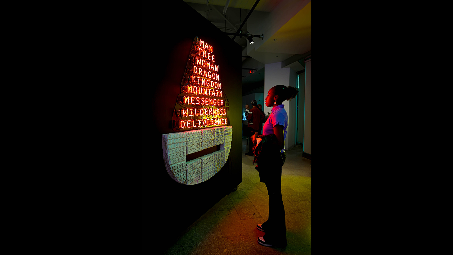 A gallery visitor looks at an installation with lights.