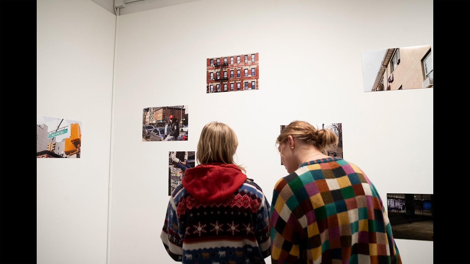 Two students look at work on a gallery wall.