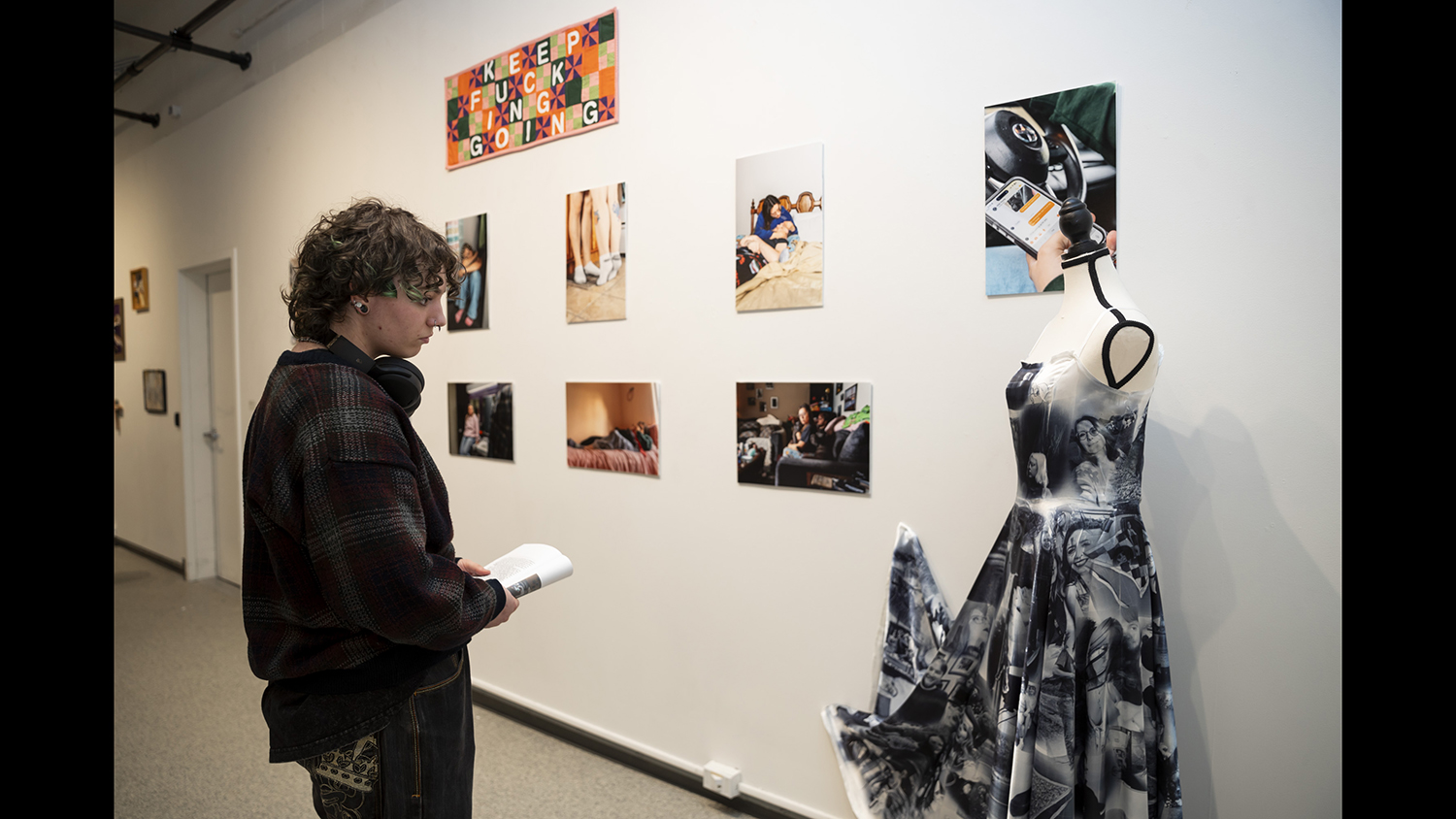 A person looks at a installation and photos on a wall.