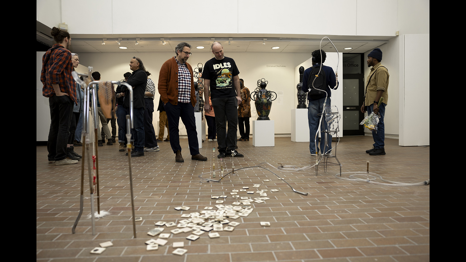 Gallery visitors look at a sculpture on the floor.