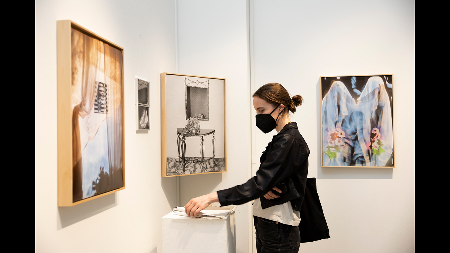 A gallery visitor looks at work on a wall.