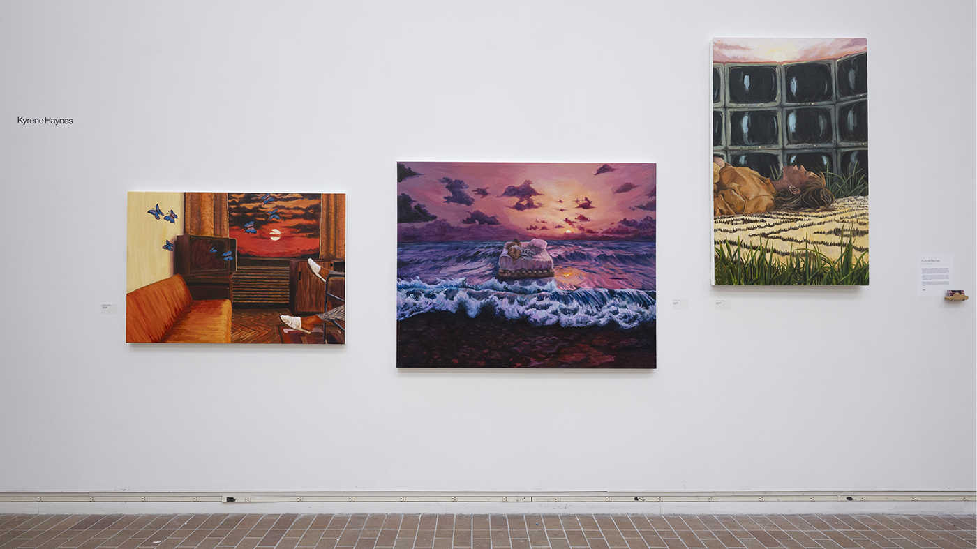 Paintings hang on a gallery wall.