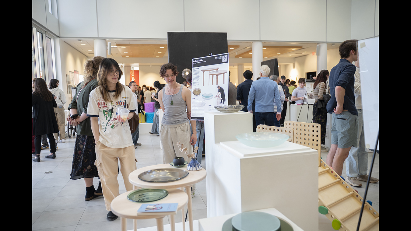 Gallery visitors look at industrial design capstone projects.