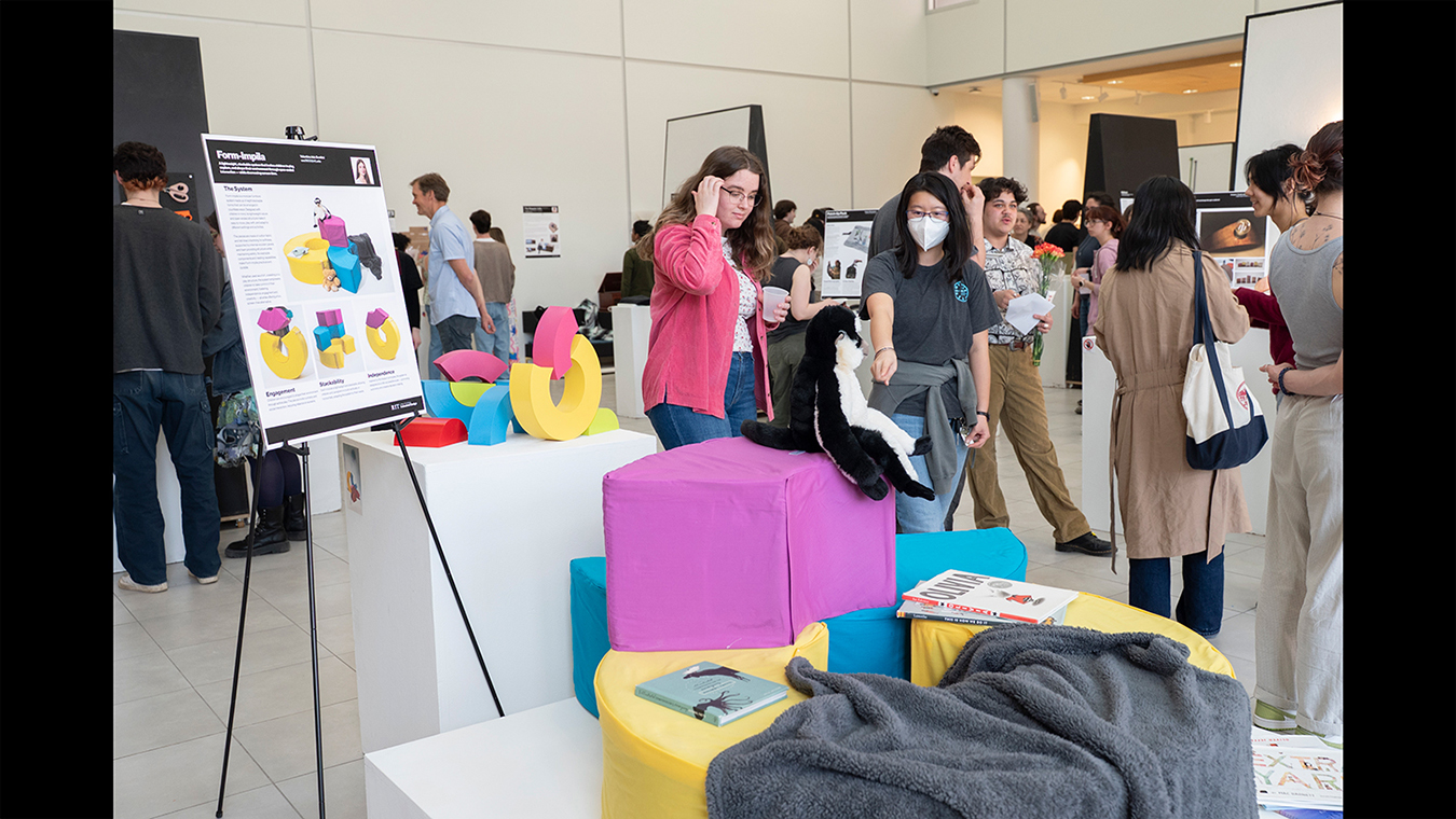 Gallery visitors look at industrial design capstone projects.