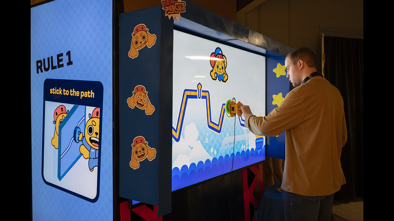 An Imagine RIT visitor interacts with a screen.