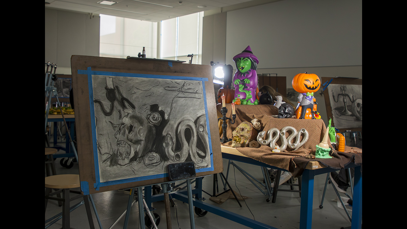 A Halloween-themed still-life setup with witches, pumpkins, and other decorations.