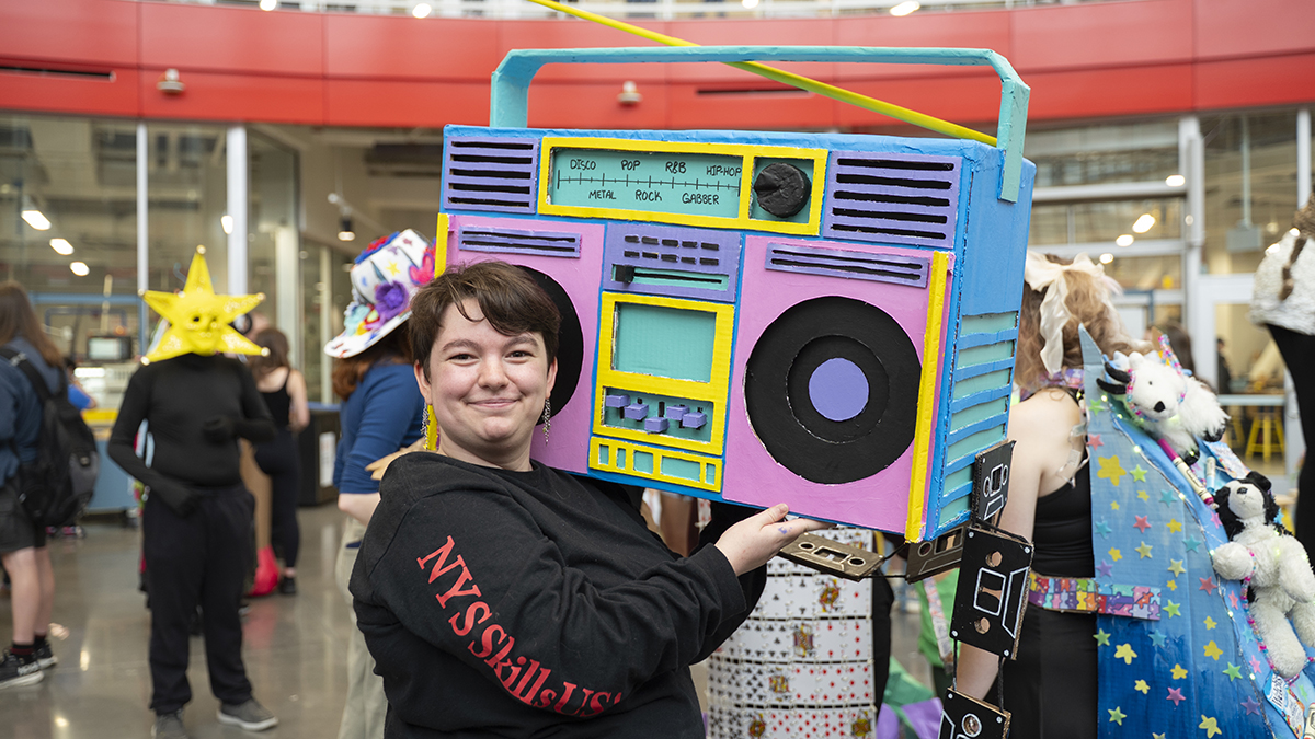 A student shows off the vibrant, analog stereo they made out of cardboard.