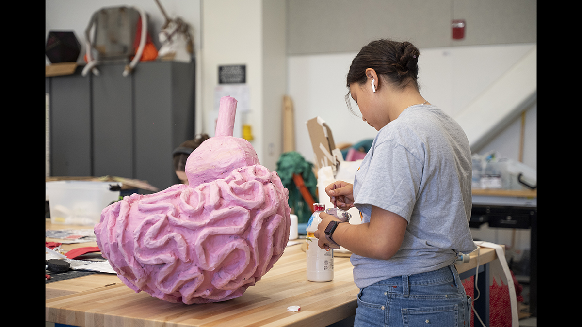 A student works on a large brain sculpture.