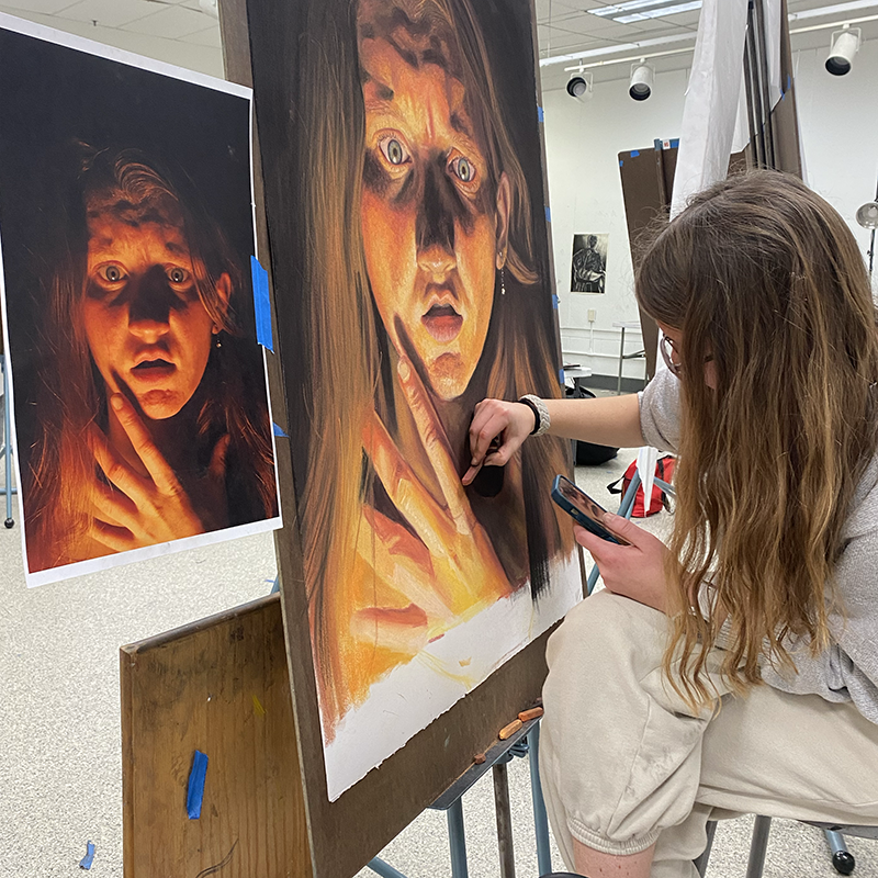 A student draws at an easel.