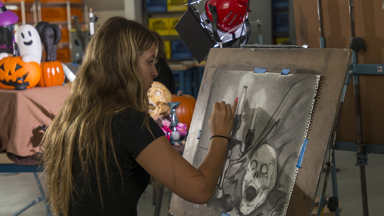 A student draws a Halloween-themed still life.