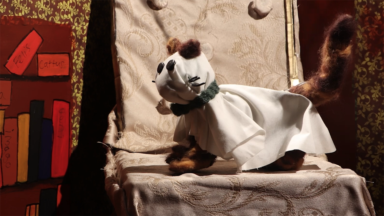 A stop motion puppet cat dressed as a ghost.