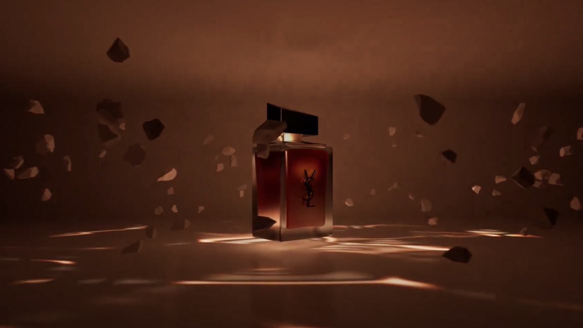 A glass bottle of perfume set against breaking glass and a brown background.