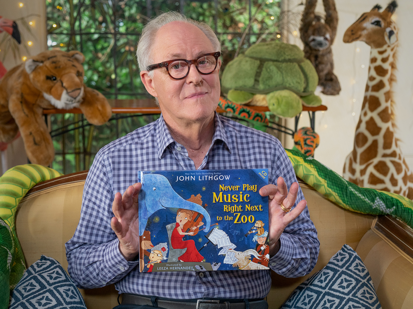 Actor John Lithgow holds up an illustrated children's book cover.