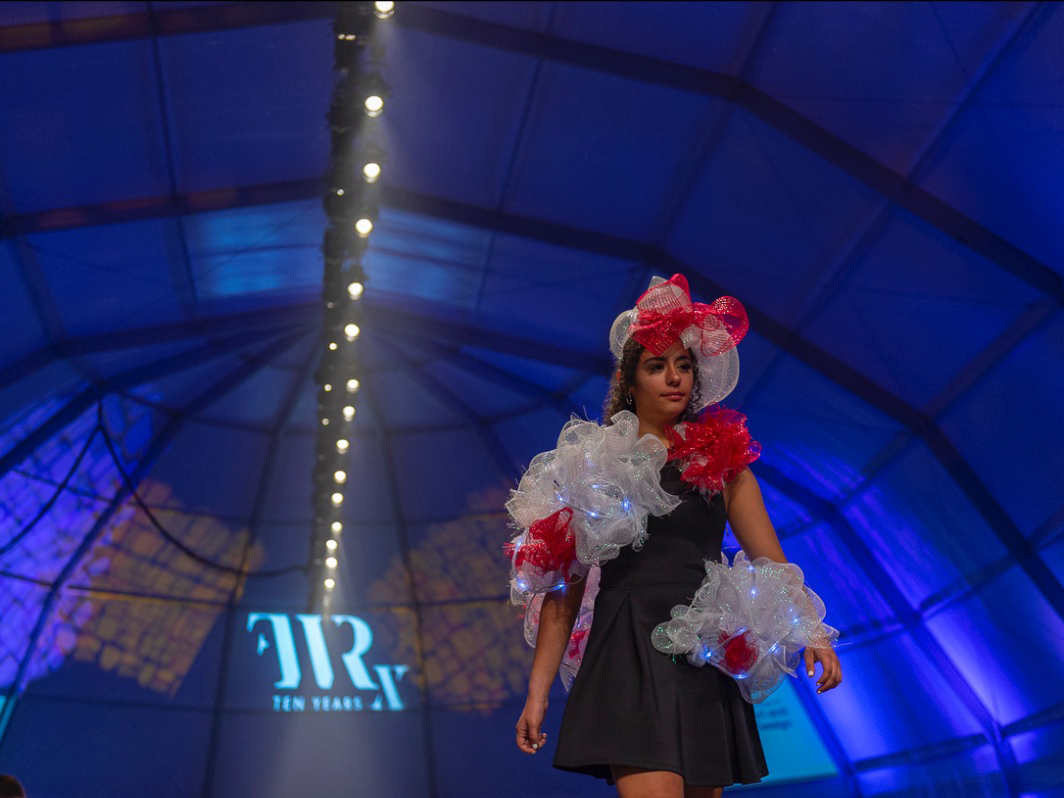 A student walks on a fashion show runway in self-designed wearable sculpture.