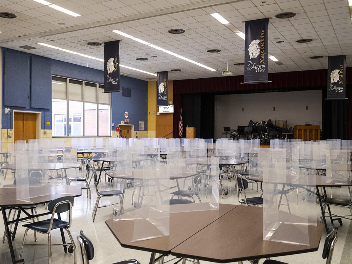 A photo of a school cafeteria with dividers at the tables to promote social distancing.