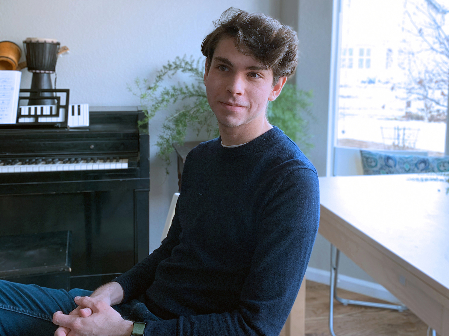A portrait of Will McCloskey set against a window and piano.
