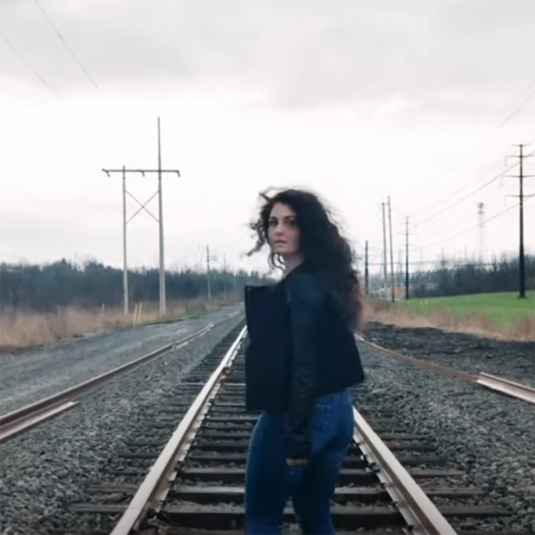 A person on train tracks looks back.