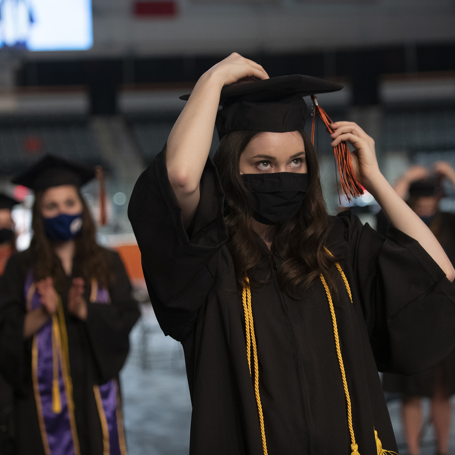 A student donning regalia at a commencement ceremony.