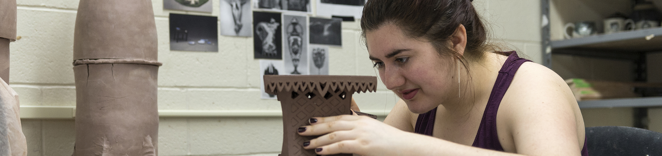 A student works on the fine details of a ceramics project.