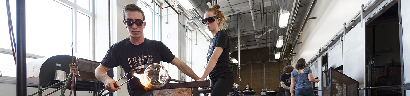 Two student blow glass in RIT's hot shop.