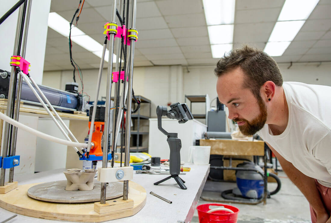 A person watching a ceramic 3D printer print with clay.