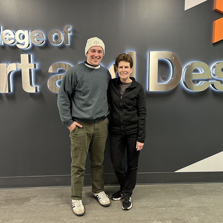 Emmitt White and Lorrie Frear in front of a College of Art and Design sign.