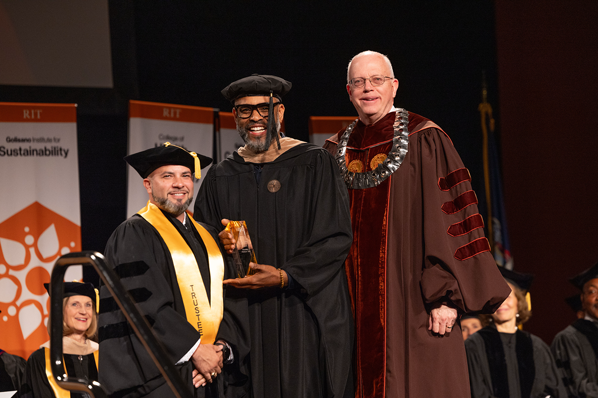 Kwaku Alston accepts his Outstanding Alumnus Award from RIT President David Munson and president of the alumni association.